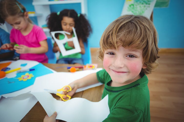 Unos niños sonrientes hacen el corte del jardín de infancia