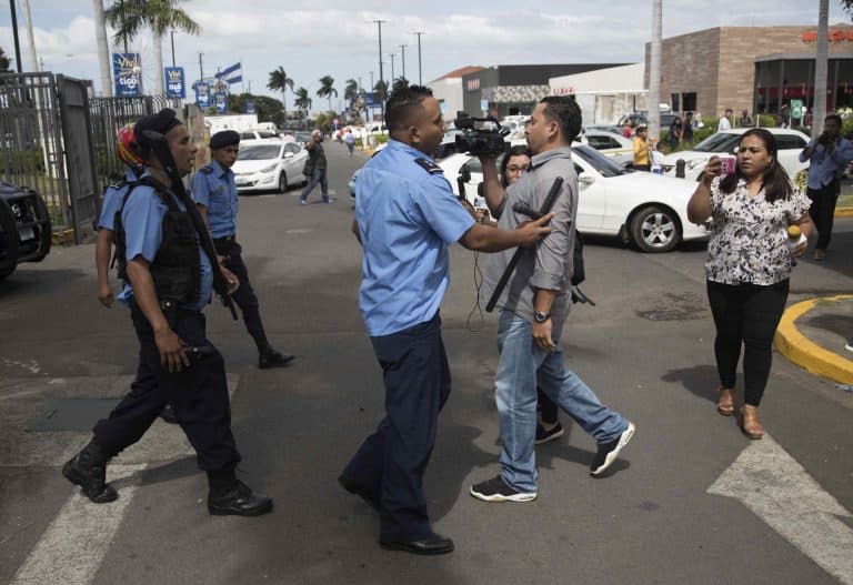 Periodistas de Nicaragua son reprimidos por policías en una calle.