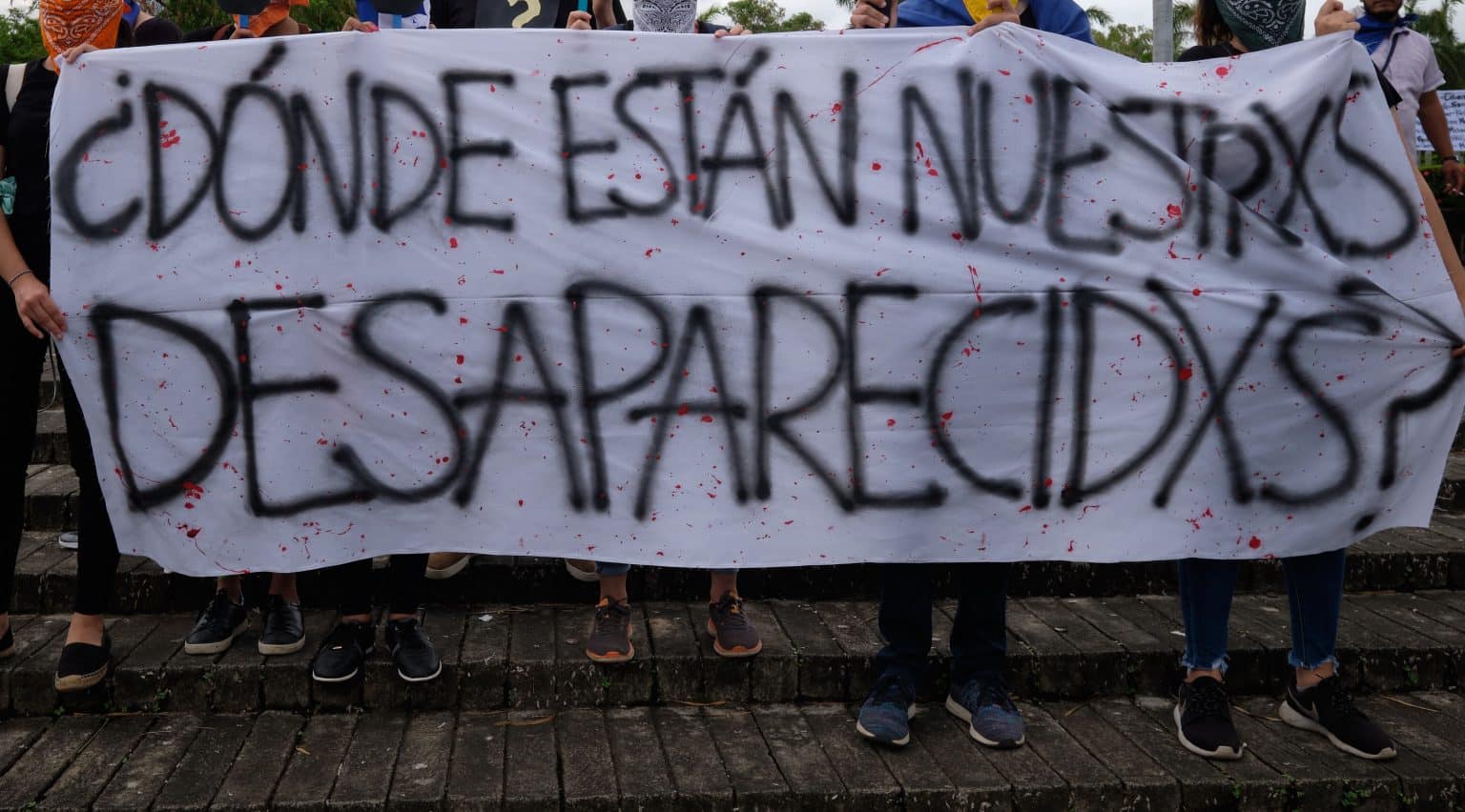 Groups of people hold up a banner asking: “Where are our Missing [Prisoners] in Nicaragua?”