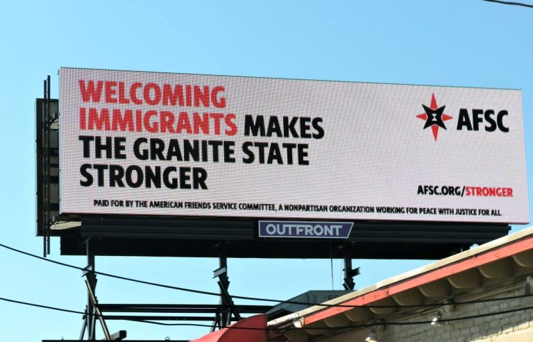 A billboard on a highway entering New Hampshire reads: “Welcoming immigrants strengthens the Granite State.”