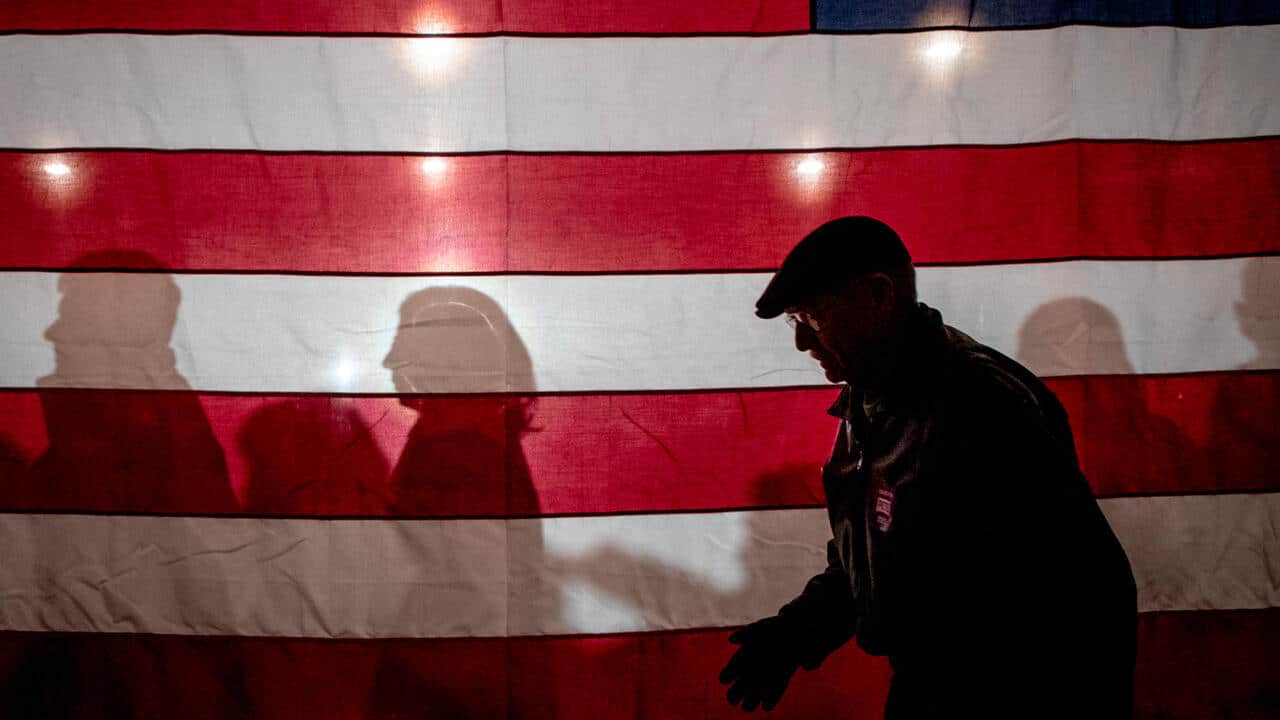 Personas junto a una bandera estadounidense.